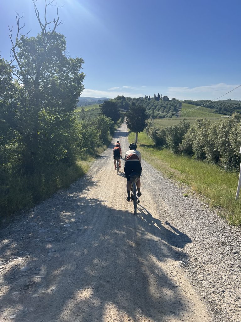 Gravel bike resting on a strade bianche white road in Tuscany with rolling Chianti hills and cypress trees in the background
