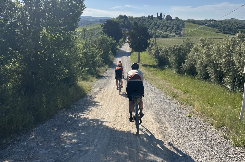 Gravel bike resting on a strade bianche white road in Tuscany with rolling Chianti hills and cypress trees in the background
