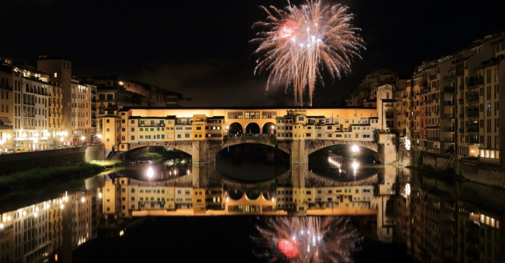 Fireworks of San Giovanni in Florence rising over the Arno and the bridges at night