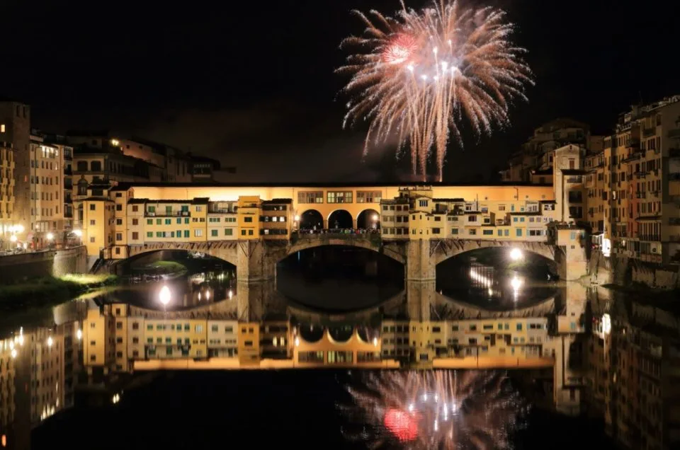 Fireworks of San Giovanni in Florence rising over the Arno and the bridges at night