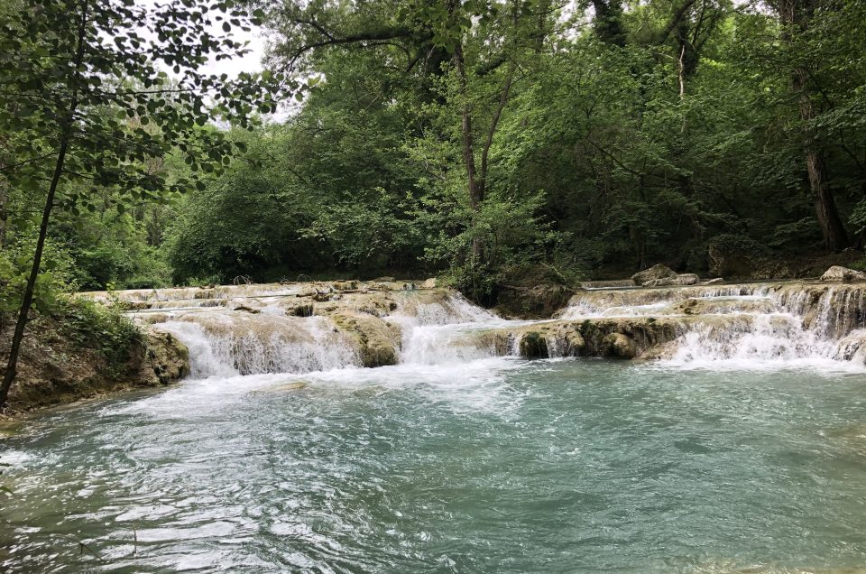 Turquoise river pool below a waterfall, a classic wild swimming in Tuscany spot near Florence