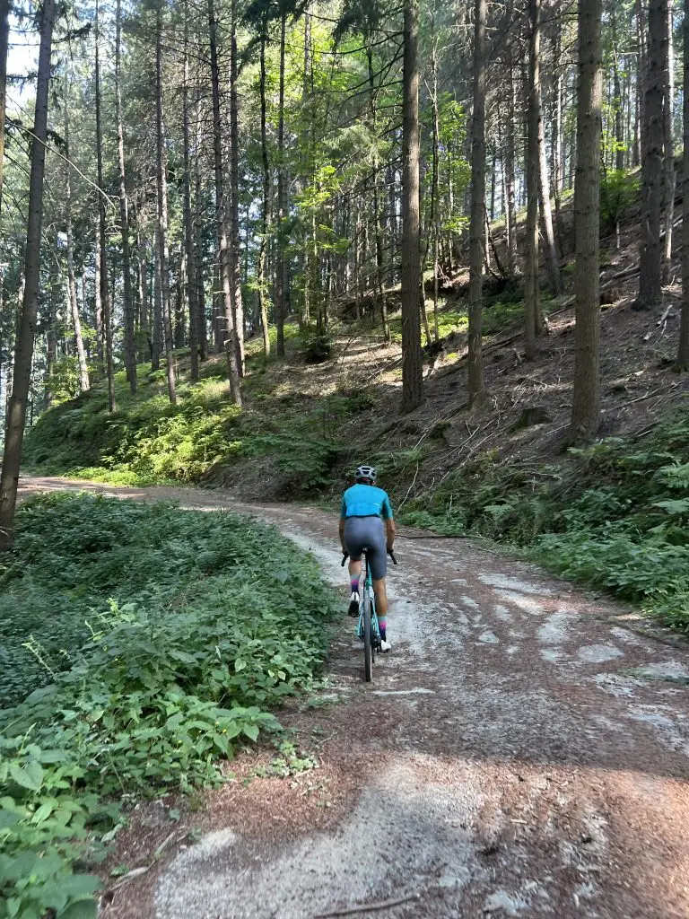 Gravel cyclist riding a shaded forest road through Vallombrosa on the La Leonessa gravel route in Tuscany